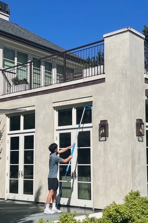 Next View Cleaning technician cleaning tall windows with an extension pole